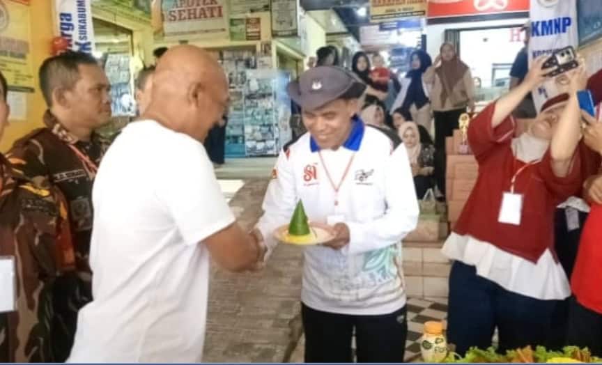 Koordinator pasar Cibadak memotong tumpeng dalam perayaan HUT RI ke-81.